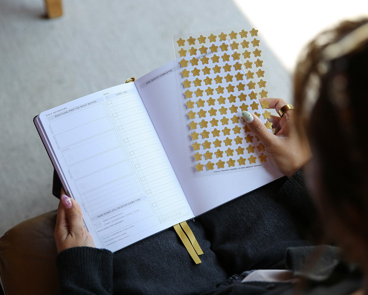 Person sitting on a chair with a notebook and star-shaped stickers.