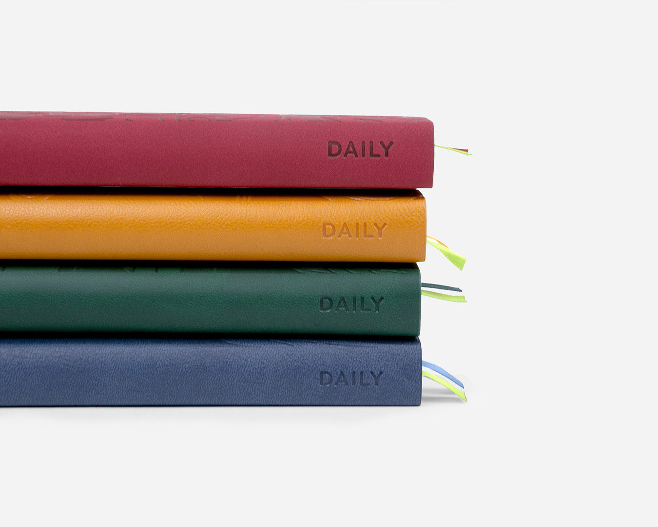 Four colorful planners titled 'DAILY' stacked on a light gray background