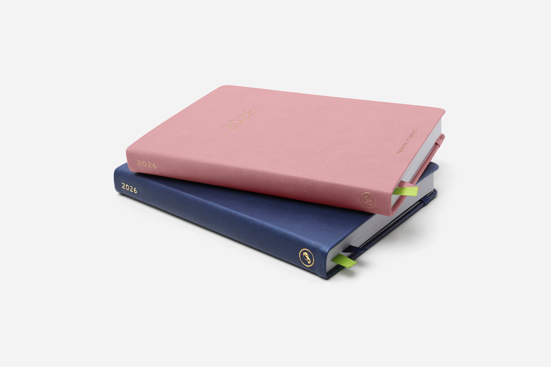 Two hardcover planners, one pink and one blue, stacked on a white background