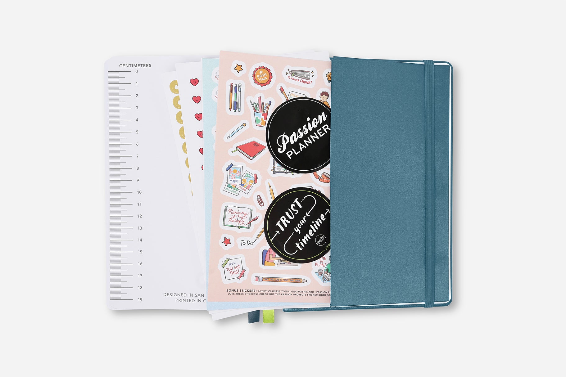 Teal planner with stickers and open pages on a white background