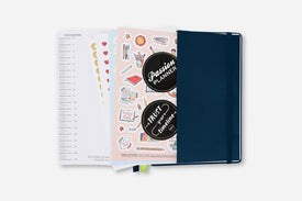 Planner with stickers and a navy cover on a white background