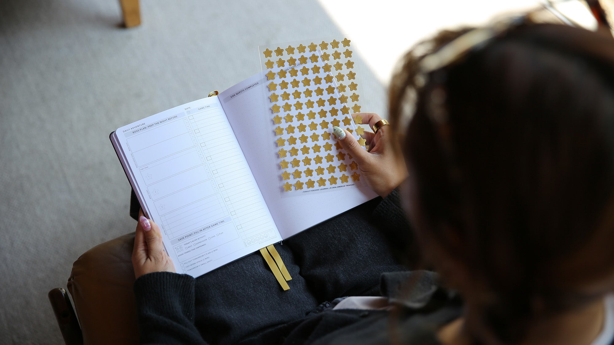 Person sitting on a chair with a notebook and star-shaped stickers.