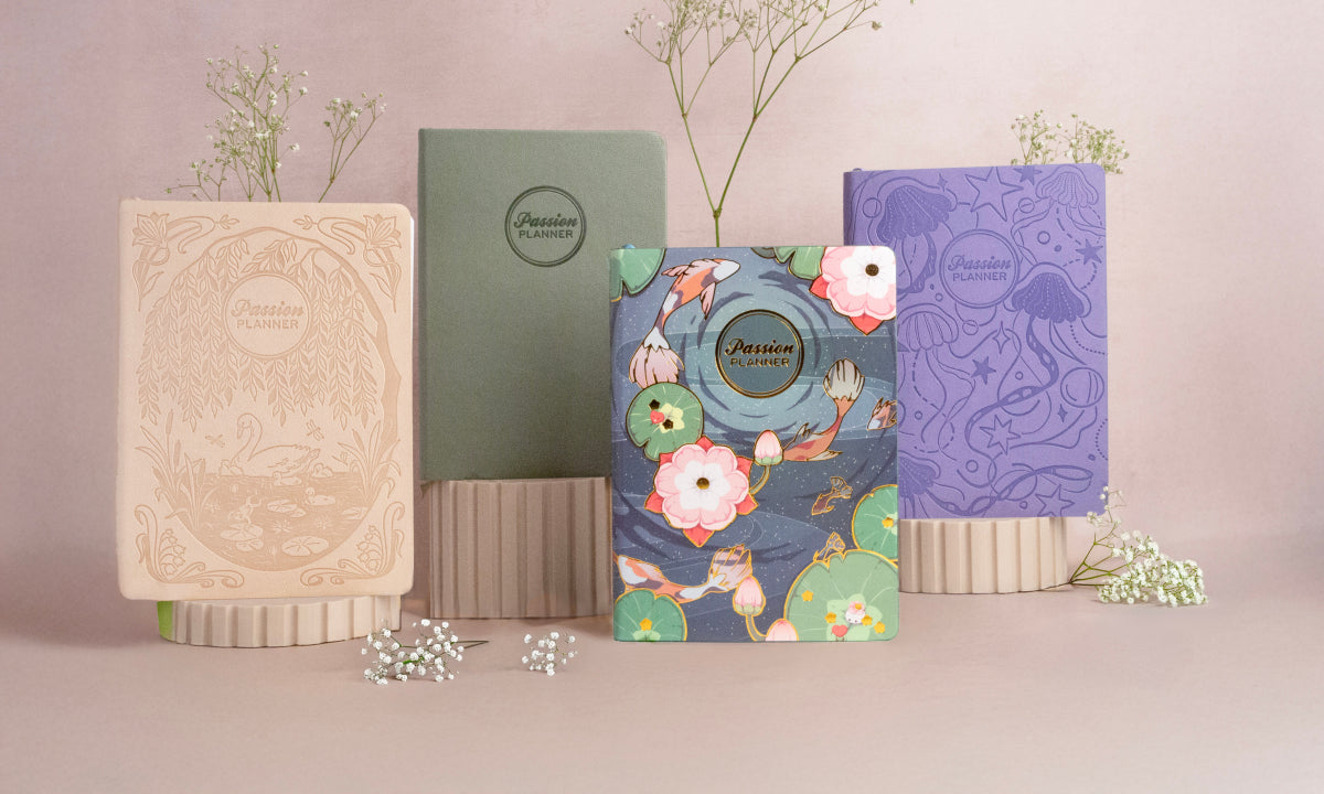 Set of four mid-year planners with different cover designs on a light pink background