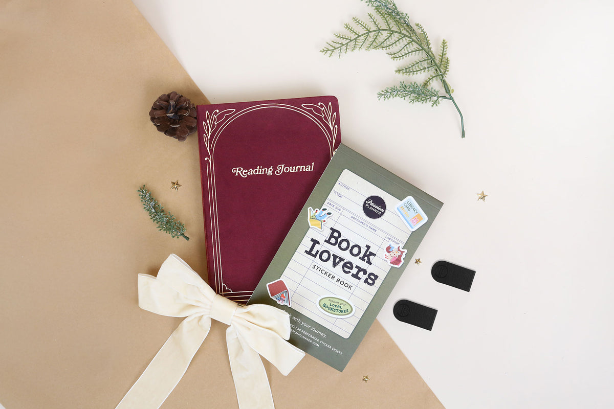 Red reading journal and 'Book Lovers' sticker book on a beige and white background