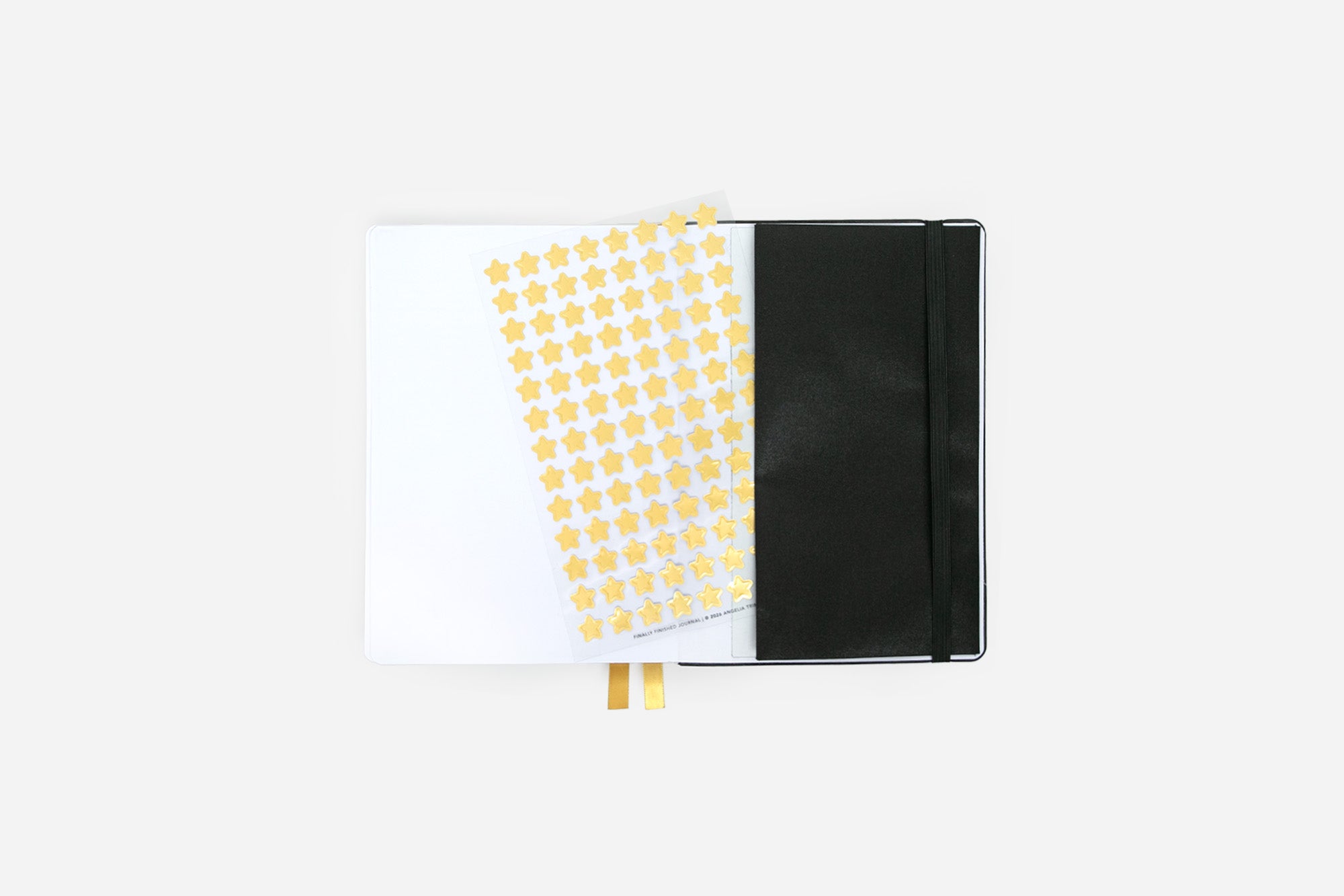 Journal with a black cover and yellow star stickers on a transparent sheet on a white background