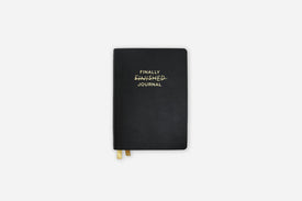Black journal with 'FINALLY FINISHED JOURNAL' text on a white background