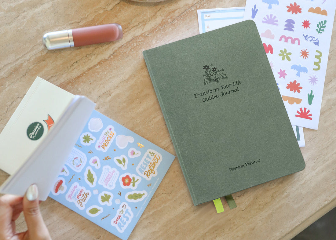 Green guided journal with stickers on a wooden desk