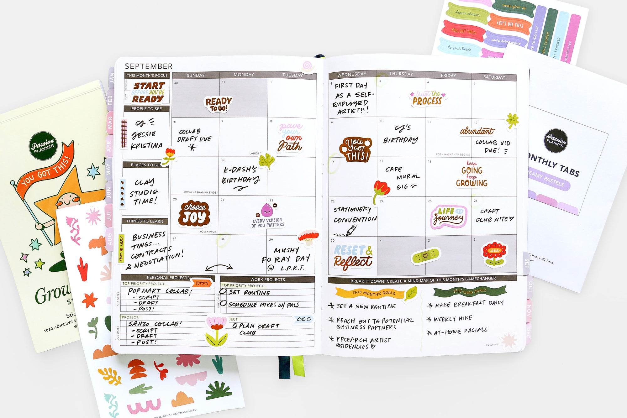 Planner with monthly tabs and stickers on a white surface