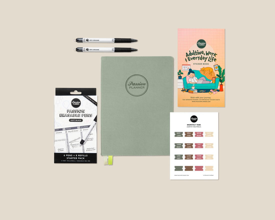 Collection of stationery items including a planner, pens, and a sticker book on a beige background