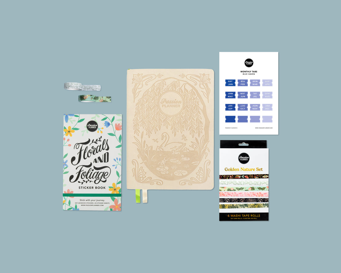 Collection of stationery items including a weekly planner with swan cover, sticker book, and washi tape rolls on a blue background