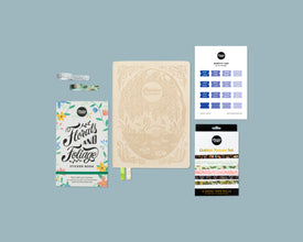 Collection of stationery items including a weekly planner with swan cover, sticker book, and washi tape rolls on a blue background