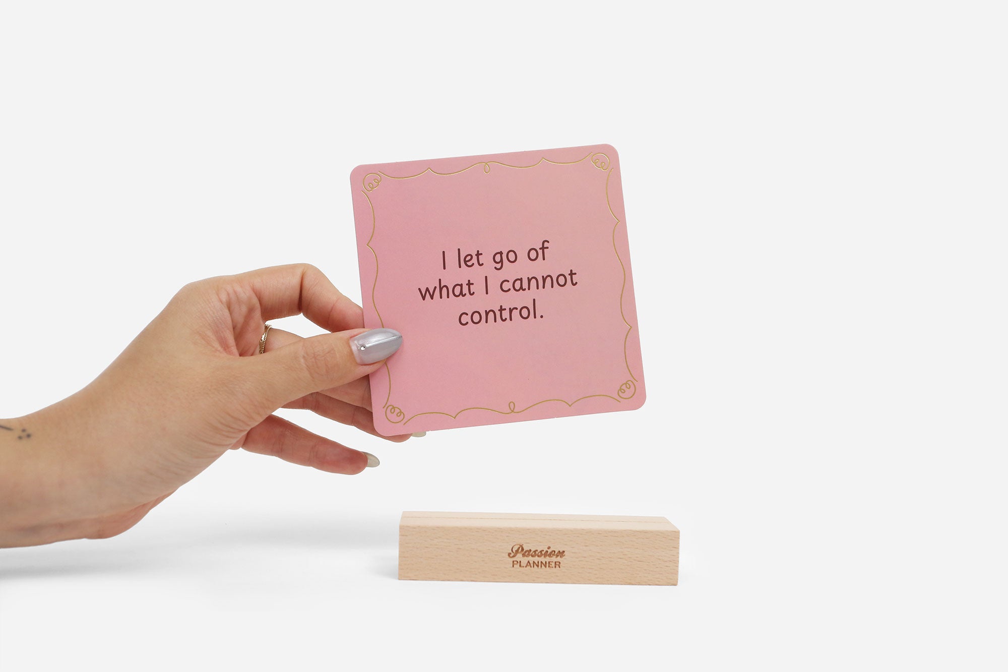 Hand holding a pink affirmation card with text on a white background