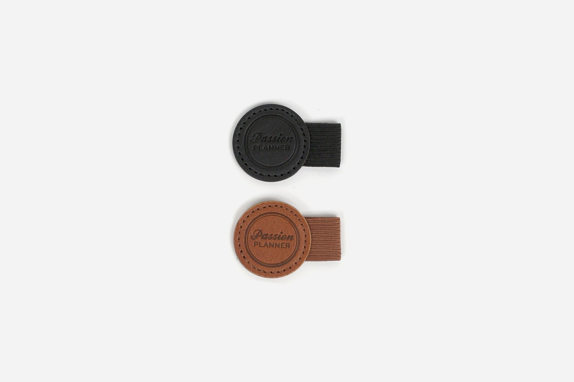 Two leather-like pen loops, one black and one brown, on a white background.