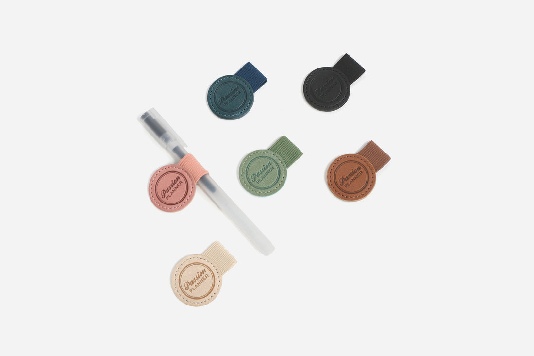 Set of colorful circular pen loops with a pen on a light gray background