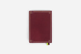 Maroon reading journal with decorative gold edges on a white background